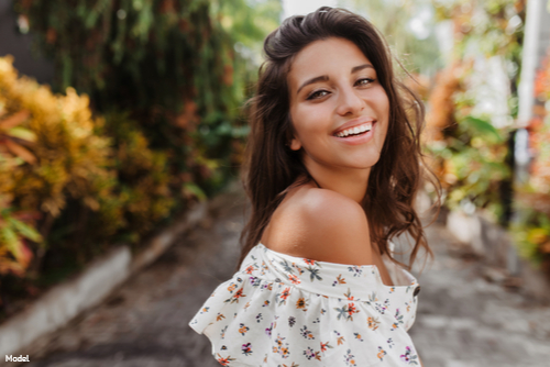 Confident, joyful woman with brown hair outdoors smiling