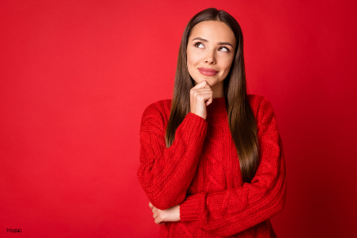 woman smuling, pondering thoughts while wearing red sweater
