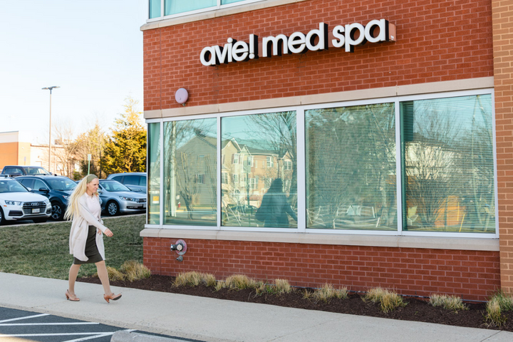 A blonde, middle-aged woman walking in front of Avie! Med Spa to her facial appointment.